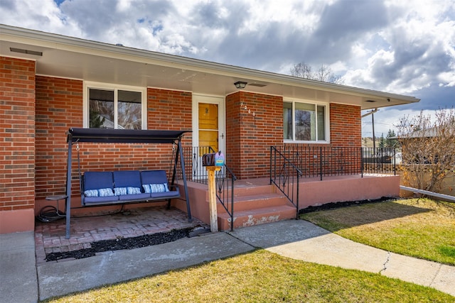 view of exterior entry with covered porch and brick siding