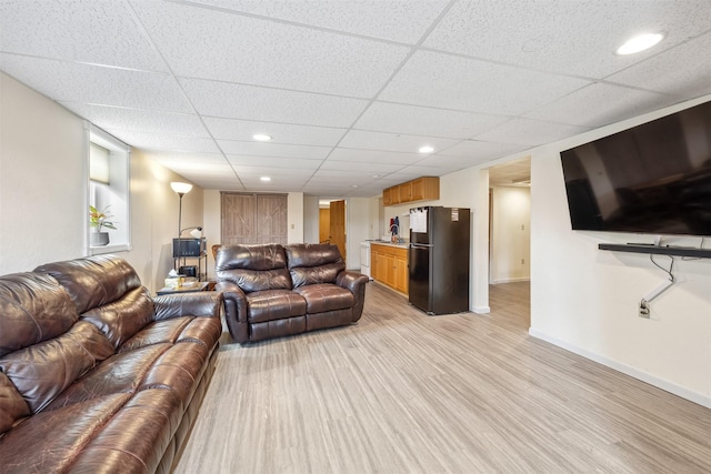 living room with indoor bar, baseboards, a drop ceiling, and light wood finished floors