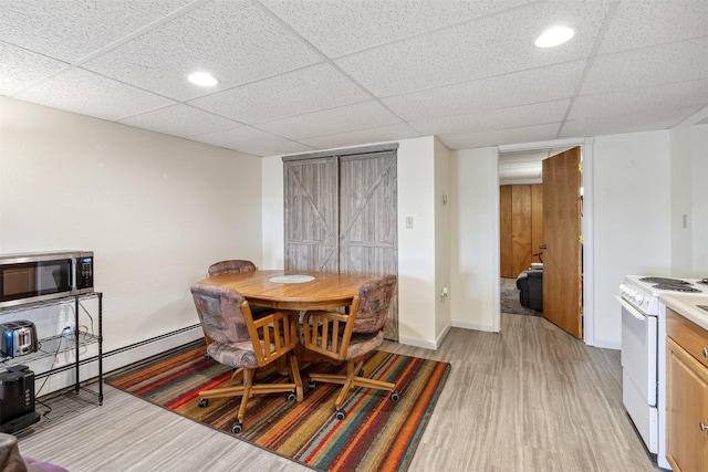dining space featuring baseboards, a baseboard radiator, light wood-style flooring, and a drop ceiling