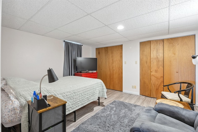 bedroom with baseboards, recessed lighting, light wood-style flooring, and a drop ceiling
