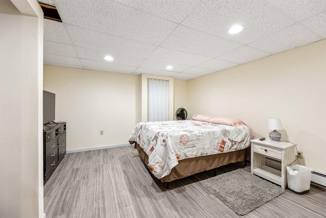 bedroom with baseboards, recessed lighting, a paneled ceiling, and wood finished floors