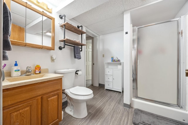 bathroom featuring vanity, a stall shower, wood finished floors, and toilet