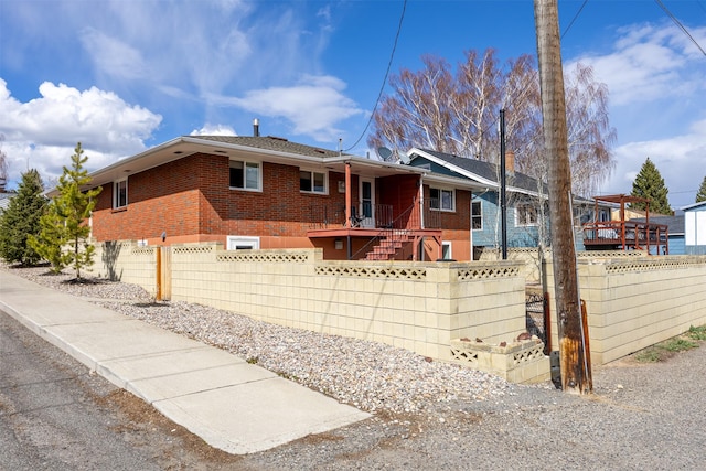 single story home featuring brick siding, a fenced front yard, and stairs