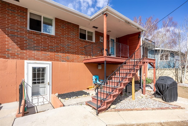 rear view of house with stairway and brick siding