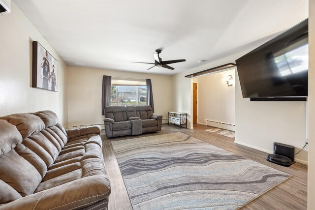 living area with baseboards, ceiling fan, wood finished floors, and baseboard heating