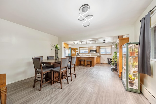 dining area featuring baseboards, a baseboard radiator, light wood-type flooring, and ceiling fan