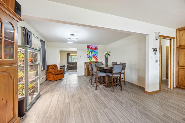 dining room featuring light wood-style floors, baseboards, and a baseboard radiator