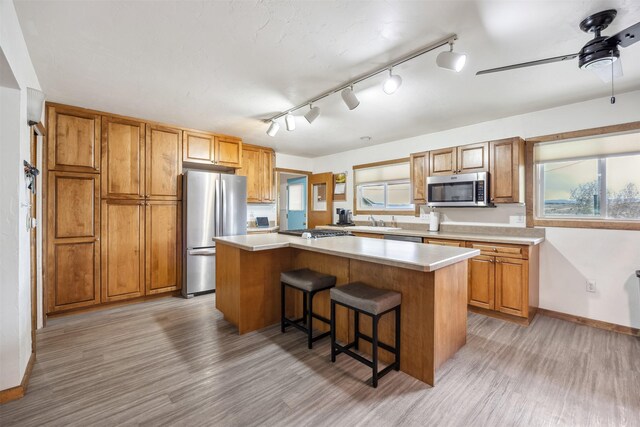 kitchen with stainless steel appliances, a center island, a sink, and light wood-style floors