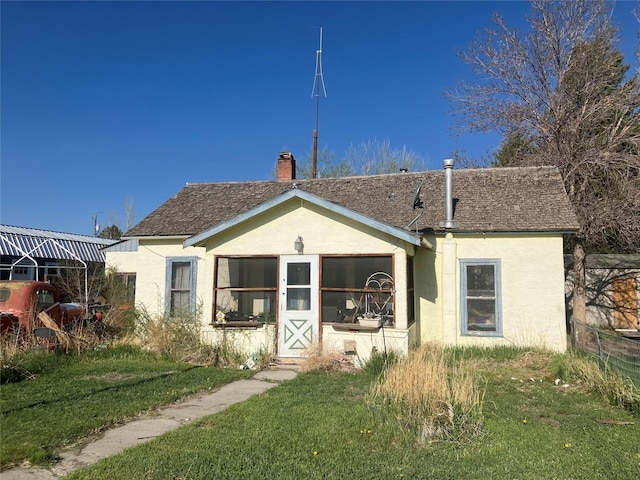 view of front of property featuring a chimney, stucco siding, and a front yard