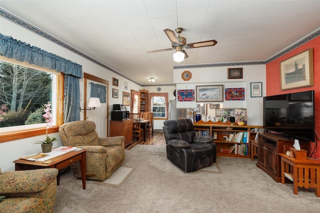 living room featuring ceiling fan, ornamental molding, and light colored carpet