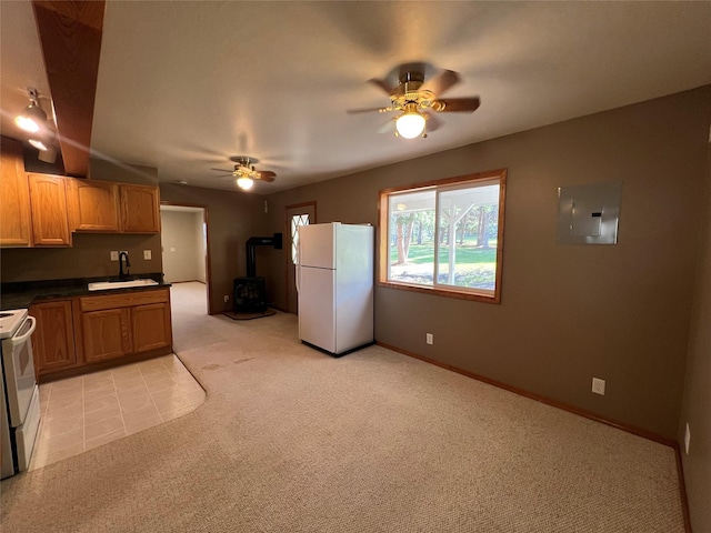 kitchen with electric panel, a ceiling fan, a wood stove, a sink, and white appliances