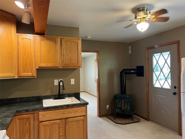 kitchen with a sink, a ceiling fan, light carpet, and dark countertops