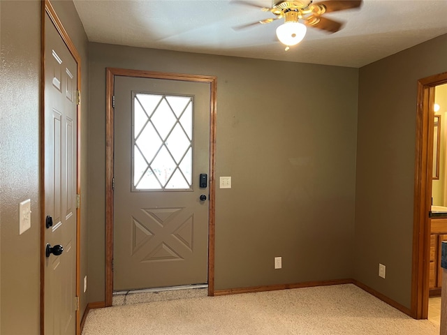 doorway featuring baseboards, ceiling fan, and light carpet