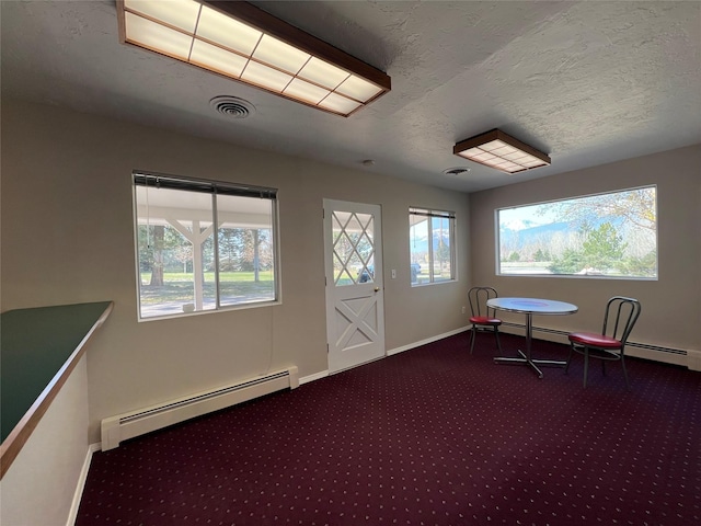 interior space featuring a textured ceiling, visible vents, baseboard heating, baseboards, and carpet