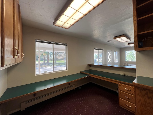 unfurnished office featuring dark carpet and a baseboard heating unit