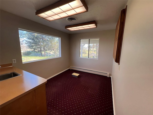 unfurnished room with visible vents, a sink, carpet floors, a baseboard radiator, and baseboards