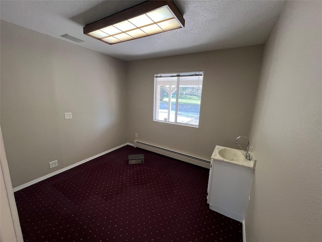 carpeted empty room featuring a sink, baseboards, a baseboard radiator, and visible vents