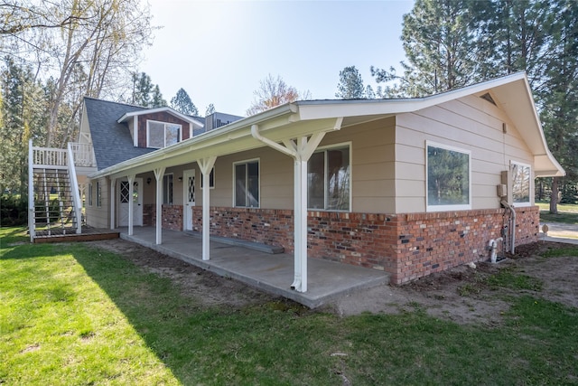 view of front of property with stairway, a porch, a front lawn, and brick siding