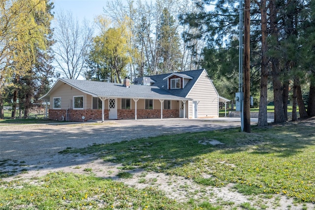 view of front of property with brick siding, a front lawn, driveway, and covered porch