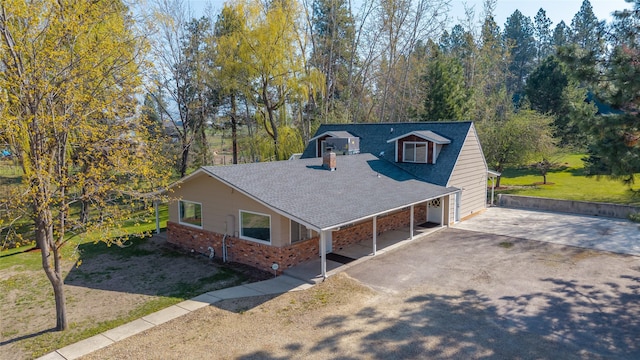 exterior space featuring a shingled roof, driveway, and brick siding