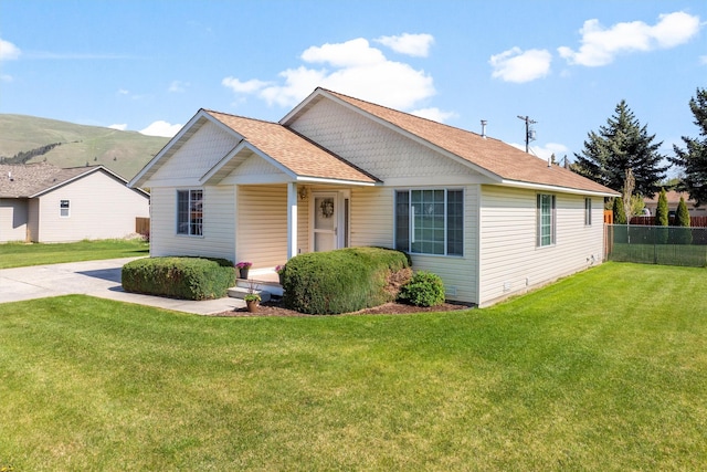 view of front of home with a porch, fence, roof with shingles, and a front lawn