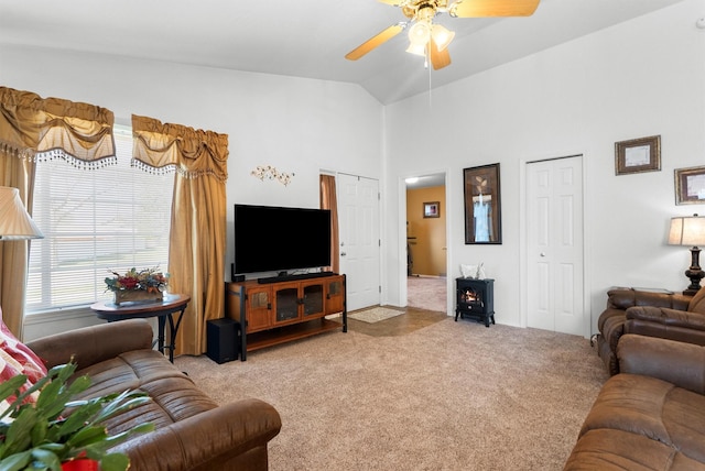 living area featuring carpet floors, ceiling fan, a wood stove, and high vaulted ceiling