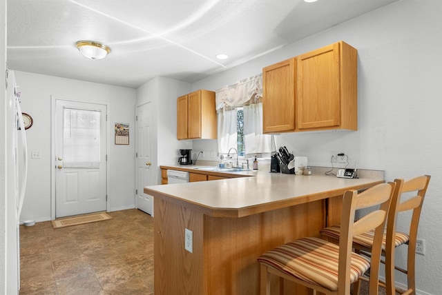 kitchen featuring a peninsula, white dishwasher, a kitchen breakfast bar, light countertops, and a sink