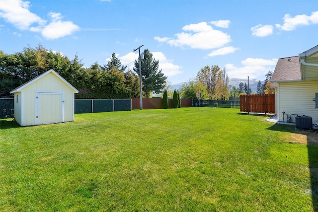 view of yard with a fenced backyard, a storage unit, an outdoor structure, and central AC