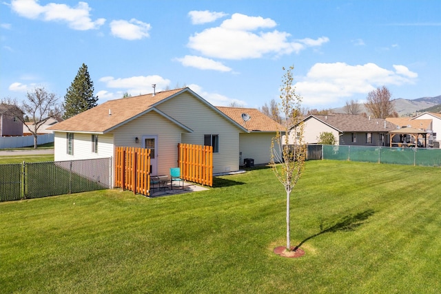 rear view of house featuring a fenced backyard, a patio, and a yard