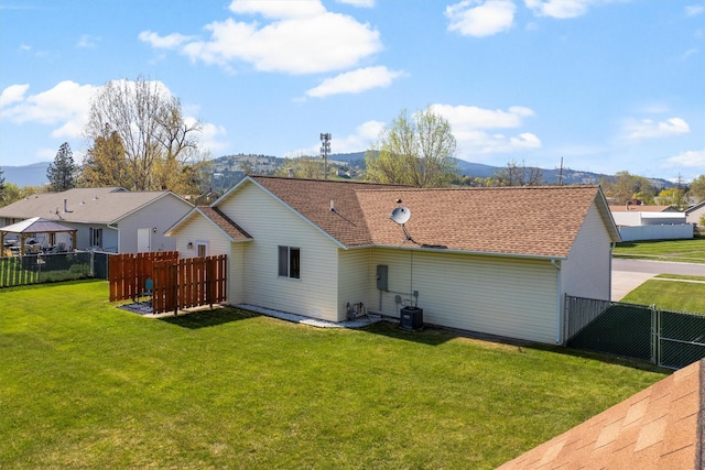 rear view of property with a yard, fence, central AC unit, and a mountain view