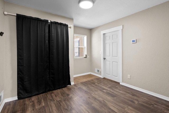 empty room featuring baseboards and dark wood finished floors