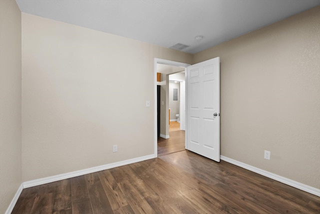 unfurnished bedroom with baseboards and dark wood-style floors