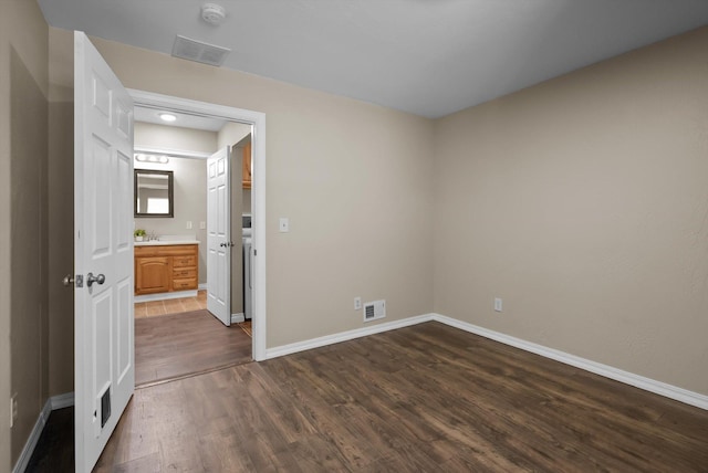 spare room featuring baseboards, dark wood-style flooring, and visible vents