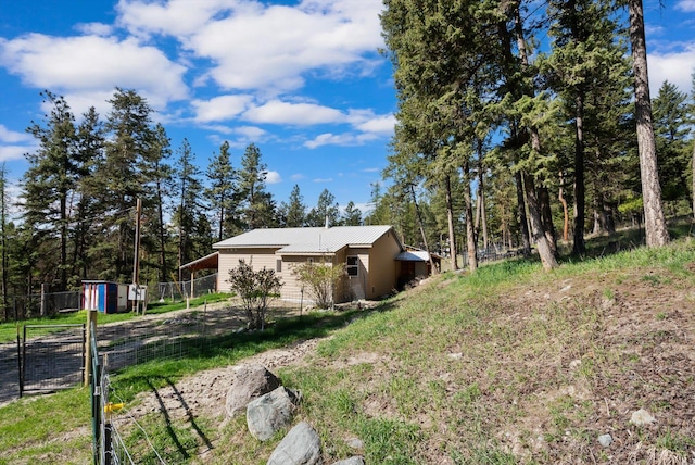 view of side of property featuring fence, a storage unit, an outbuilding, and metal roof