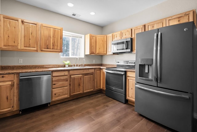 kitchen with a sink, light brown cabinets, stainless steel appliances, dark wood-type flooring, and visible vents