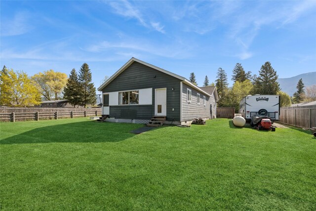 1020 3rd Ave E, Columbia Falls, MT 59912 - rear view of property with entry steps, a mountain view, a yard, and a fenced backyard