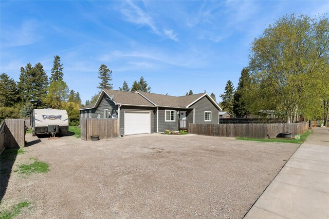 1020 3rd Ave E, Columbia Falls, MT 59912 - view of side of property featuring an attached garage, a shingled roof, fence, and driveway