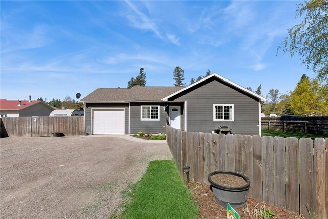 1020 3rd Ave E, Columbia Falls, MT 59912 - view of front of property featuring fence, an attached garage, driveway, and a shingled roof