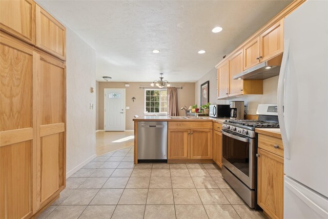 1020 3rd Ave E, Columbia Falls, MT 59912 - kitchen with a notable chandelier, appliances with stainless steel finishes, a sink, a peninsula, and under cabinet range hood