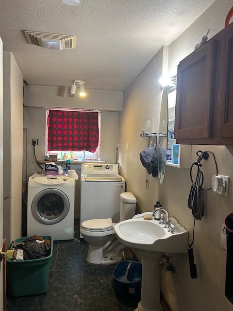 bathroom with washer and dryer, a textured ceiling, and toilet