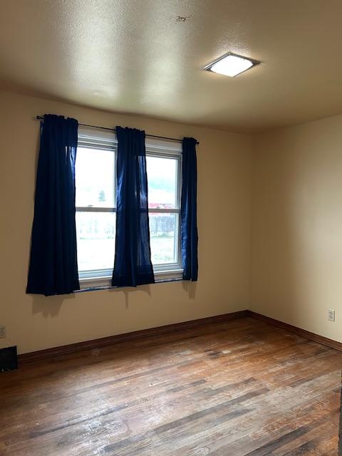 spare room featuring hardwood / wood-style flooring and baseboards