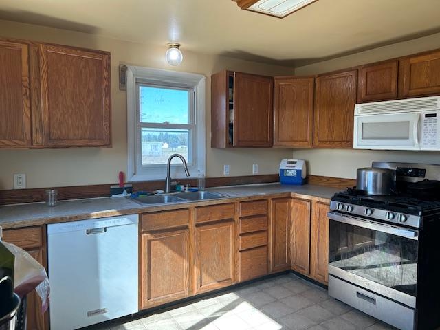 kitchen with white appliances, a sink, and brown cabinetry