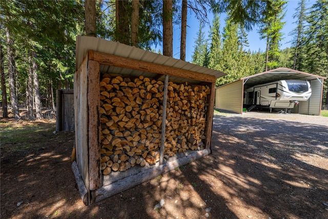 view of outdoor structure with driveway and a detached carport