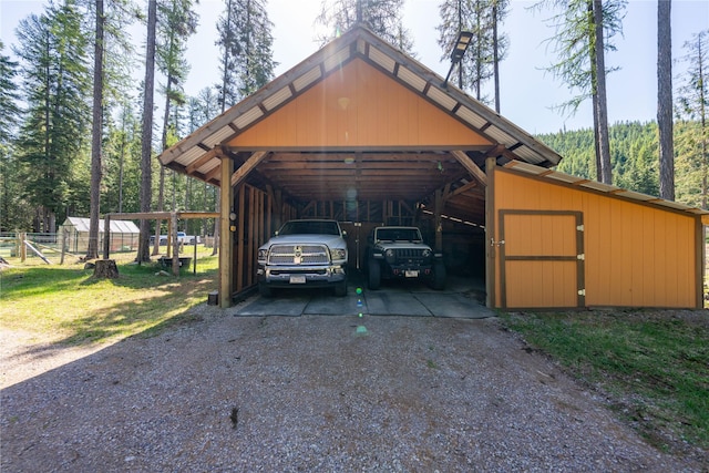 view of car parking featuring fence, driveway, and a detached carport