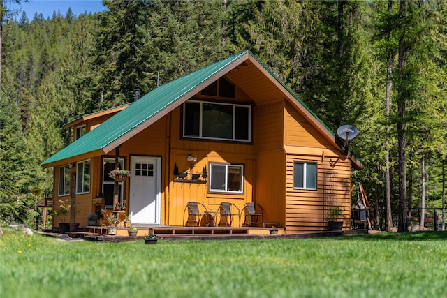 view of front of home with a forest view, metal roof, and a front yard
