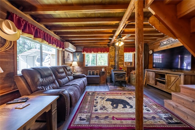living area with wood ceiling, a wall unit AC, a wood stove, beam ceiling, and wood finished floors