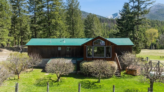 exterior space with metal roof, a view of trees, a mountain view, a yard, and stairway