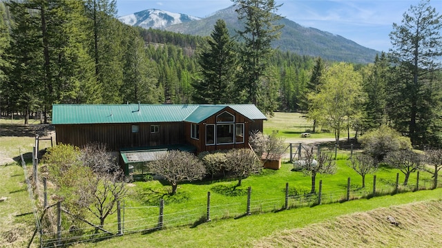 back of property featuring fence, metal roof, a mountain view, a yard, and a forest view