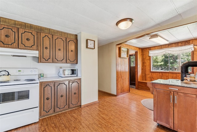 kitchen featuring light countertops, under cabinet range hood, white appliances, and light wood-style flooring