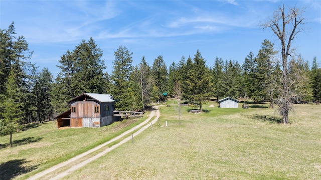 view of yard with a barn, an outdoor structure, and dirt driveway